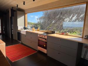 a kitchen with a large window and a large sink at Admirals Cabin in Currie +8 photos