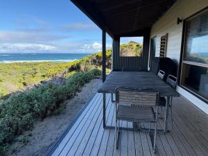 a wooden deck with a table and chairs on the beach at Admirals Cabin in Currie