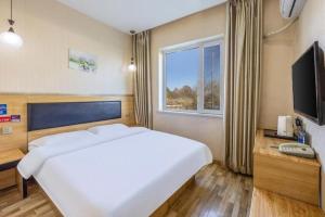 a bedroom with a large white bed and a television at Jun Hotel Beijing Miyun County Railway Station in Nanmujiayu