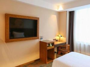a hotel room with a bed and a television on the wall at James Joyce Coffetel Changchun People's Square in Changchun