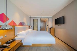 a bedroom with a large white bed and a flat screen tv at Borrman Hotel Zhanjiang Wuchuan Jinsha Plaza in Zhanjiang