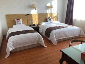 two beds in a hotel room with wood floors at Pai Hotel Ordos Dongsheng District Yingbin Road in Ordos