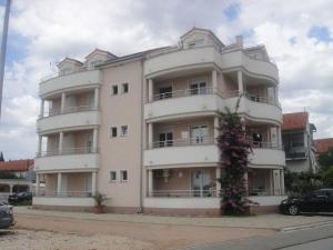 a large white building with a flowering tree in front of it at Apartments Angie in Biograd na Moru