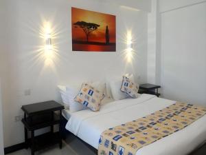 a bedroom with a white bed with two tables at Sapphire Hotel in Kampala