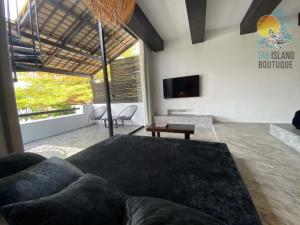 a living room with a couch and a tv at Tao Island Boutique Hotel in Koh Tao