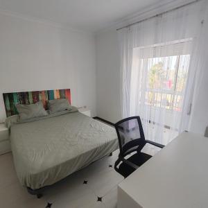 Un dormitorio con una cama y una silla y una ventana. en Casa Álamo, en Puerto Real