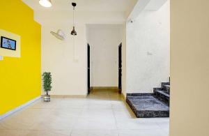 a hallway with yellow and white walls and a potted plant at Hotel O VSV Avenue Hennur in Bengaluru