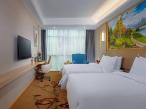 a hotel room with two beds and a television at Vienna Hotel Jiangxi Ji'an Jinggangshan in Jinggangshanzonghekenzhichang