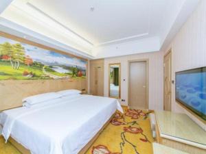 a bedroom with a large bed and a flat screen tv at Vienna Hotel Chengdu North Railway Station North Square Wukuaishi Metro Station in Chengdu
