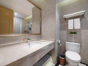 een badkamer met een wastafel, een toilet en een spiegel bij Vienna Hotel Jiangsu Kunshan Qiandeng Town in Qiandun +56 foto's