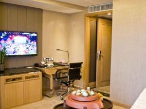 a room with a desk and a television on a wall at Venus Royal Hotel Guangdong Meizhou Huangjia Mingdian in Meizhou