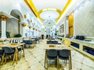 un restaurant avec des tables, des chaises et un lustre dans l'établissement Vienna Hotel Hunan Yueyang Linxiang, à Yueyang