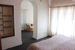una camera da letto con un letto, uno specchio e una sedia di Snow Leopard Lodge a Srinagar