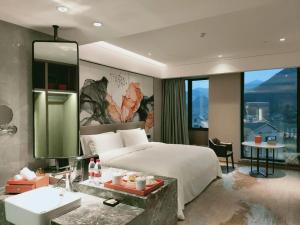 une chambre avec un lit, un lavabo et un miroir dans l'établissement Yinhu Junyi Hotel（Wildlife Park）, à Hangzhou