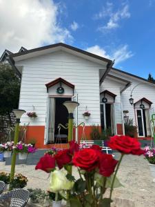 ein weißes Haus mit roten Blumen davor in der Unterkunft Homestay Selena Đà Lạt in Da Lat