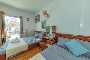 ein Schlafzimmer mit zwei Betten und einem Fenster in der Unterkunft Homestay Selena Đà Lạt in Da Lat + 45 Fotos