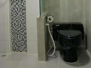 a bathroom with a black toilet and a shower at 189 Resort in Ban Khlong Samrong