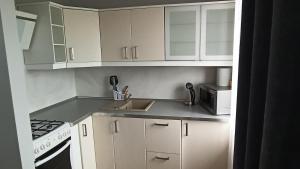 a kitchen with white cabinets and a sink and a microwave at Small studio in the city center in Kutno