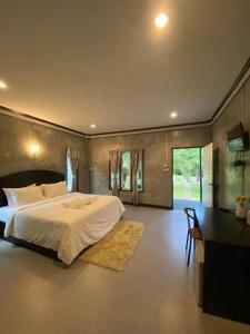 une chambre avec un grand lit blanc et un bureau dans l'établissement V Valley Resort, à Satun