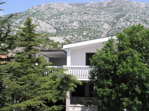 a white house with a mountain in the background at 35 meters from sea Apartment Keser and House for rent in Karlobag