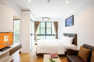 a bedroom with a bed and a couch and a tv at B2 Sriracha Premier Hotel in Si Racha +21 photos