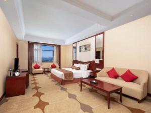 a hotel room with a bed and a couch at Longqi Jianguo Hotel Kunshan in Suzhou