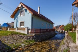 a blue house with a stone wall next to a river at Apartmánový Dom River in Blatnica