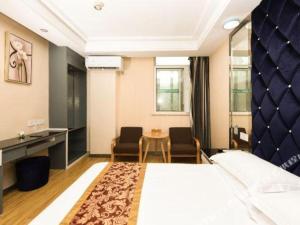 a hotel room with a bed and a table and chairs at GreenTree Alliance Ningbo Metro South Changshou Road Branch in Ningbo