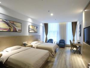 a hotel room with two beds and a flat screen tv at GreenTree Inn Anhui Hefei South Railway Station Damo Sqaure Business Hotel in Hefei +289 photos