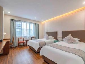 a hotel room with two beds and a table at GEM Hotel Ningbo Tongtu Road Minglou Metro Station in Ningbo +88 photos