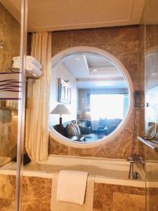 a bathroom with a round mirror and a living room at Qingdao Blue Horizon Hotel Laoshan in Qingdao
