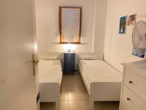 a small room with two beds and a window at Marcelli trilocale 200 mt mare giardino posto auto in Marcelli