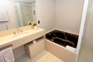 a bathroom with a sink and a bath tub at Mengo Palace Hotel in Rio de Janeiro