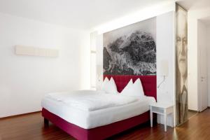 Schlafzimmer mit einem weißen Bett mit einem roten Kopfteil in der Unterkunft Hotel Payerbacherhof in Payerbach
