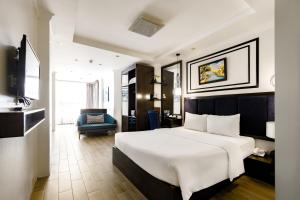 a hotel room with a white bed and a blue chair at Bella Rosa Trendy Hotel & Spa in Hanoi