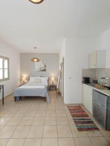 a white bedroom with a bed and a kitchen at Alezina studios in Amorgos