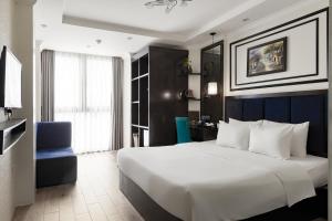a bedroom with a large white bed and a blue chair at Bella Rosa Trendy Hotel & Spa in Hanoi +66 photos