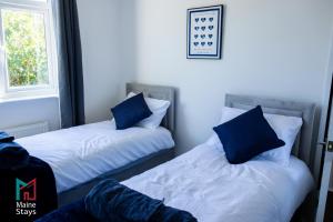 two beds with blue pillows in a room at Modern 3 Bedroom Home, 6 beds, free parking, Wi-Fi, Netflix, Near Coventry City Centre & Hospital in Coventry