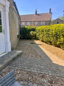 une cour avec une allée en pierre à côté d'une maison dans l'établissement Castle Cottage, à Harrogate