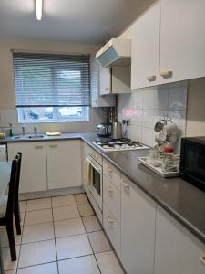 a kitchen with white cabinets and a stove top oven at Milton Keynes Lettings in Milton Keynes