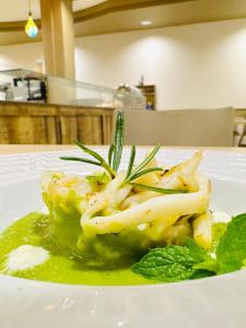 a white plate with a pasta dish with green sauce at Hotel Butterfly Wellness & Spa in Rimini