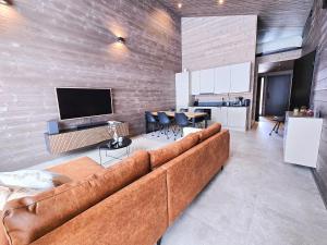 a living room with a brown couch and a tv at Villa Sienna, Äkäslompolo, Ylläs in Äkäslompolo