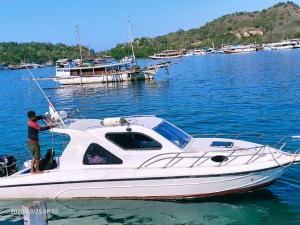 a man standing on a white boat in the water at 1 Day Fast boat trip Komodo By Bestkomodotour in Pulau Kukusan