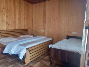 two beds in a room with wooden walls at Khoyal home stay in Jāmb