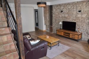 ein Wohnzimmer mit Ledercouch und Fernseher in der Unterkunft Maison de village palau del vidre in Palau-del-Vidre