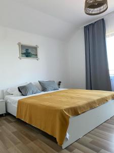 a white bedroom with a bed with a yellow blanket on it at Casa Livia in Tuzla