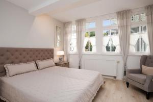 ein Schlafzimmer mit einem Bett und einem Stuhl und Fenstern in der Unterkunft Villa Eden Binz Typ 3 / Apartment 12 in Binz