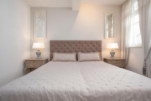 ein weißes Schlafzimmer mit einem großen Bett mit zwei Nachttischen in der Unterkunft Villa Eden Binz Typ 3 / Apartment 12 in Binz