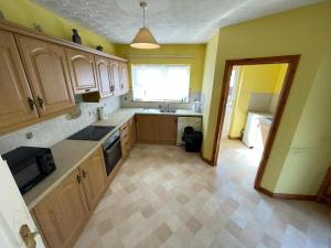 a kitchen with wooden cabinets and a sink and a window at Causeway holiday home in Ballycastle