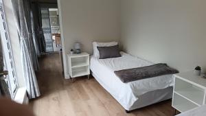 a small bedroom with a bed and a night stand at Lily Lane in Gqeberha